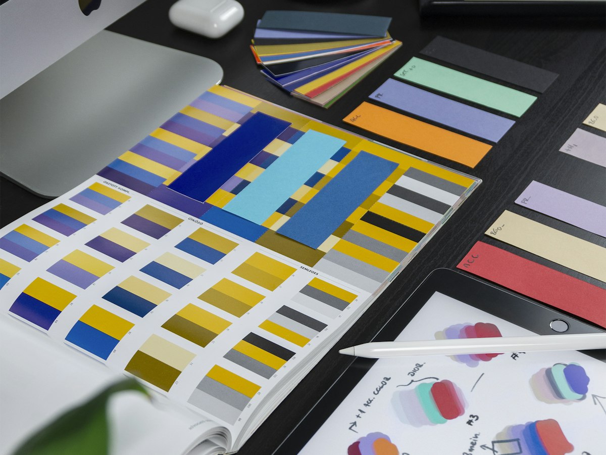 Colour swatches and palette cards spread across a designer's desk